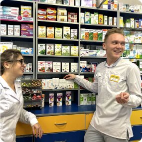 Усміхнені фармацевти біля полиць